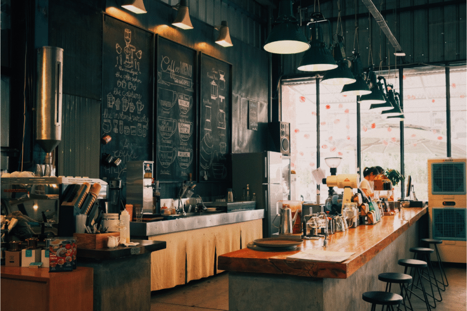 cozy coffee shop interior with chalkboard menus, warm pendant lights, and a long wooden counter with stools.